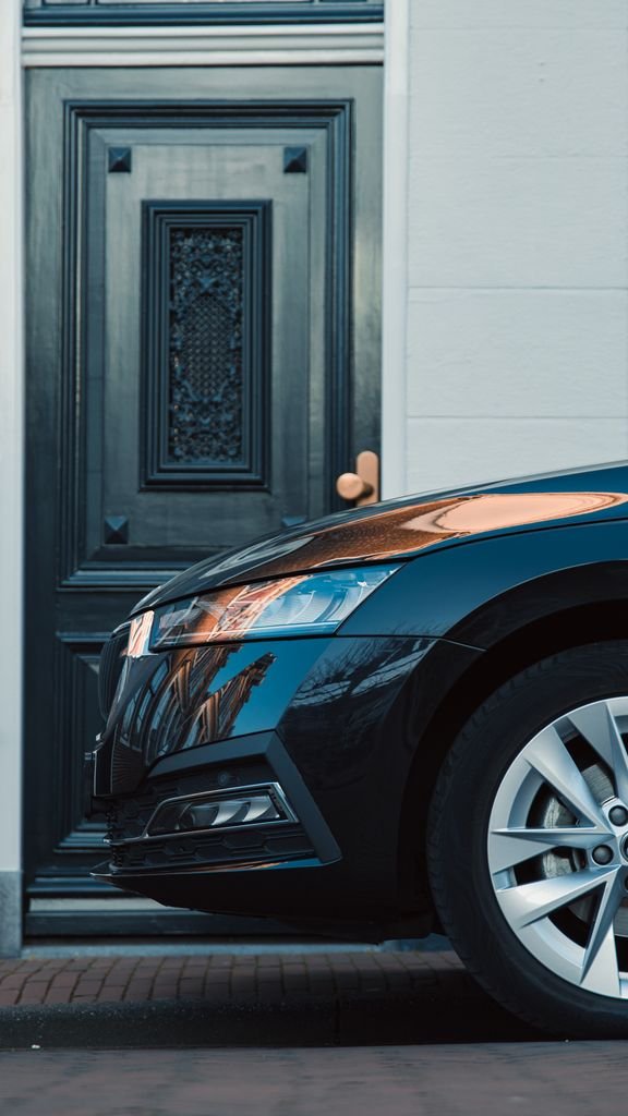 Modern black car parked in front of an ornate urban doorway.
