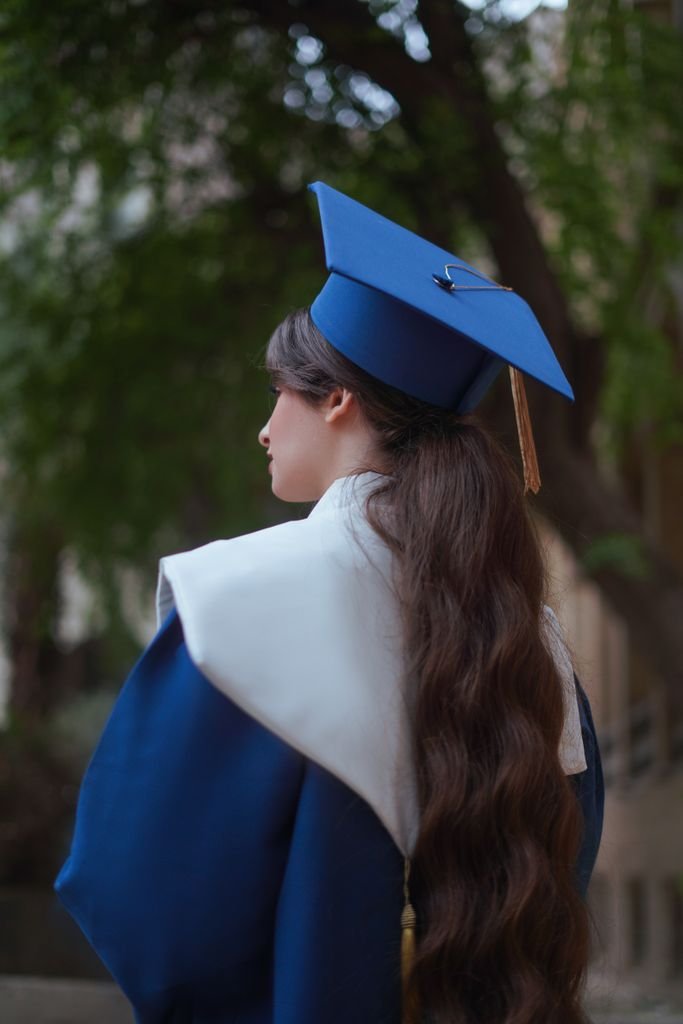 Young woman in graduation attire outdoors, symbolizing achievement and success.